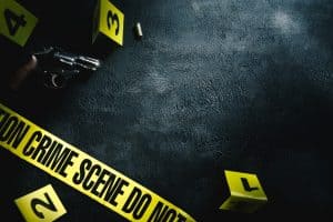 Crime scene with crime scene tape, a handgun, and numbers on signs